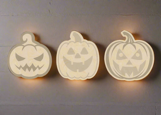 Three wooden pumpkin cutouts with jack-o'-lantern faces on a white background